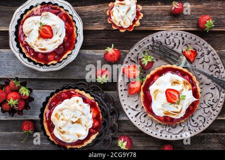 Erdbeer-Meringue-Tartlets auf rustikalem Holzhintergrund Stockfoto