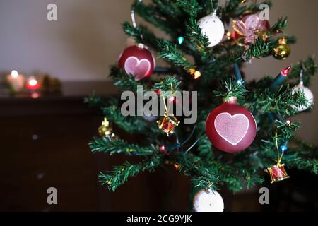 Weihnachtsbaum und herzförmige Kugeln mit Kerzen Stockfoto