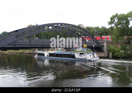 BERLIN, DEUTSCHLAND - 29. AUGUST 2020: Passagierboot an einer Eisenbahnbrücke auf der Spree vorbei Stockfoto