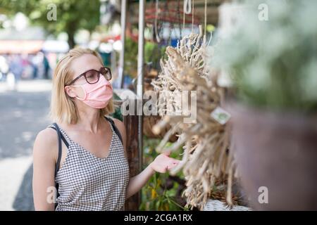 Lässige Frau, die an Marktständen im Freien einkaufen, tragen Fase-Masken zum Schutz vor einer Corona-Virus-Pandemie in München Stockfoto