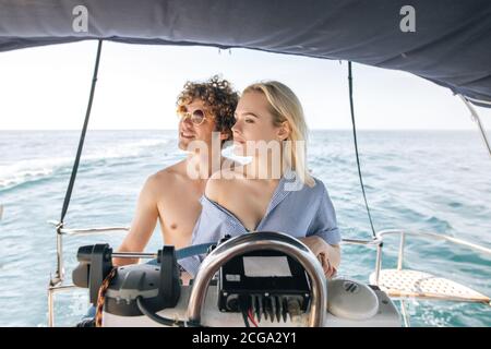 Junge männliche Kapitän Lehre seine attraktive blonde Freundin fahren Luxus Vergnügen Yacht, Sommerurlaub Konzept Stockfoto