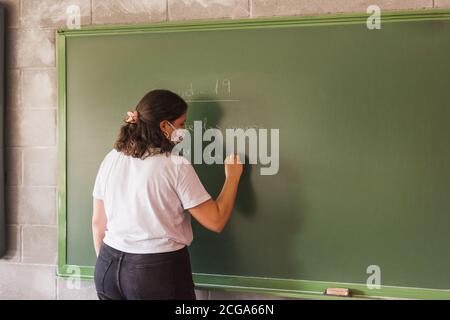 Die Lehrerin schreibt auf dem Brett die Maßnahmen, um sich zu schützen Vom Coronavius Stockfoto