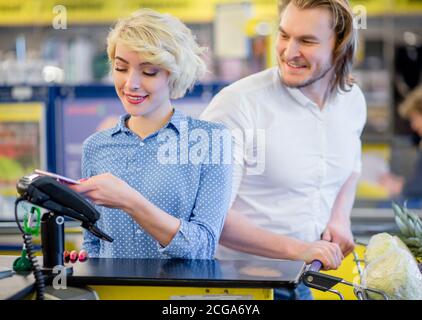 Blonde attraktive Frau an der Supermarktkasse, sie zahlt mit Kreditkarte, Shopping und Retail-Konzept. Stockfoto