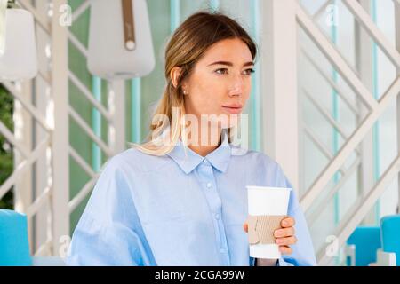 Schöne Frau trinkt Kaffee aus Kaffee recyclebare Karton Takeaway Tasse im Street Cafe. Becher Mit Kopierbereich. Leerer Raum. Stockfoto