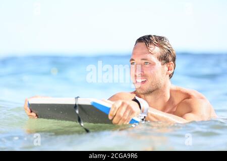 Strandmann mit Spaß im Wasser lächelt glücklich. Porträt von jungen schönen männlichen Strand Modell Surfen auf Bodyboard Stockfoto