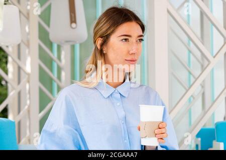 Schöne Frau trinkt Kaffee aus Kaffee recyclebare Karton Takeaway Tasse im Street Cafe. Becher Mit Kopierbereich. Leerer Raum. Stockfoto