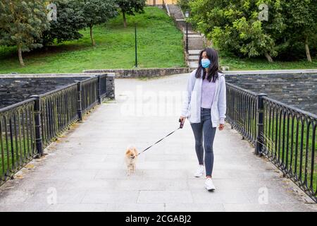 Mädchen, die während einer Pandemie ihren Hund aus Pommern in einem Park spazieren Situation Stockfoto