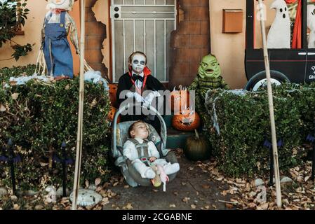 Drei männliche Geschwister in Halloween-Kostümen posieren zu Hause Stockfoto