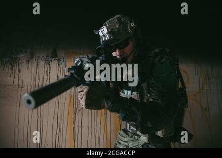 Soldat in voller US-MARSOC-Ausrüstung in verlassene Gebäude betreten, mit verschiedenen Winkeln mit MK18 Sturmgewehr zielen Stockfoto