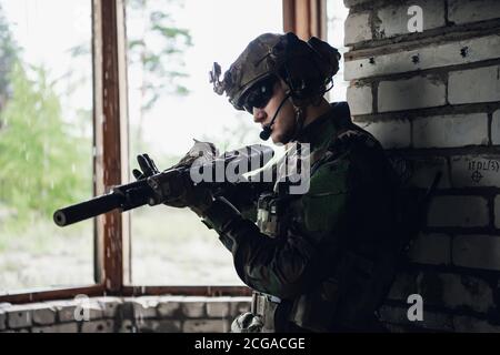 Waffeninspektion während des Wartens an einer Stelle. Militärmann überprüft sein Sturmgewehr, um sich auf den Betrieb vorzubereiten. Stockfoto