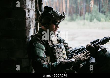 Waffeninspektion während des Wartens an einer Stelle. Militärmann überprüft sein Sturmgewehr, um sich auf den Betrieb vorzubereiten. Stockfoto