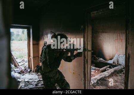 Soldat in voller US-MARSOC-Ausrüstung in verlassene Gebäude betreten, mit verschiedenen Winkeln mit MK18 Sturmgewehr zielen Stockfoto