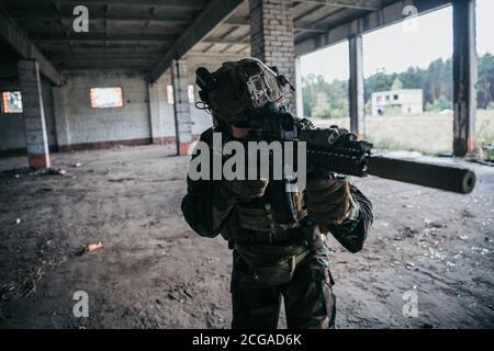 Soldat in voller US-MARSOC-Ausrüstung in verlassene Gebäude betreten, mit verschiedenen Winkeln mit MK18 Sturmgewehr zielen Stockfoto