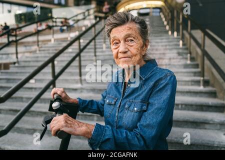 90 Jahre alte Frau mit grauen Haaren, Falten, progressive und aktive nutzt moderne Elektro-Transport-Roller. Rentnerdame nutzen umweltfreundliche Stadt Stockfoto