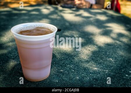 Eine kalte Tasse Bier sitzt auf einer Tischplatte im Schatten. Stockfoto