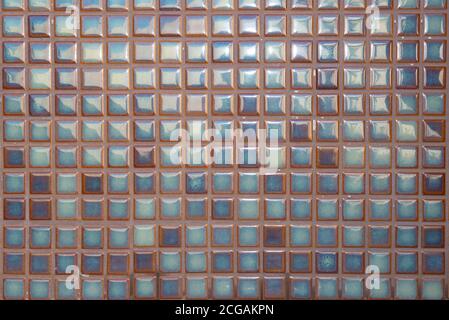 Nahaufnahme der Wand mit hellblauen quadratischen Fliesen bedeckt. Glänzende, farbenfrohe Fliesen. Abgerundete quadratische Pool Mosaik Hintergrund. Stockfoto