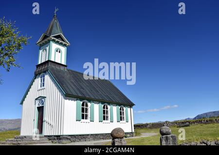 Die kleine weiße Thingvellirkirkja (Kirche) an einem hellen sonnigen Tag vor einem klaren blauen Himmel gesetzt. Thingvellir Nationalpark, Goldener Kreis, Island. Stockfoto