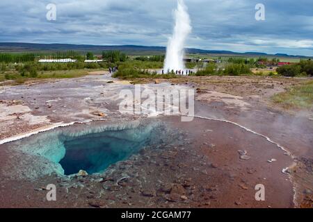 Strokkur-Geysir während einer Eruption, die vor dem südlichen Teil der Blesi-Thermalquelle im Geysir-Geothermalgebiet, dem Goldenen Kreis, zu sehen ist. Stockfoto