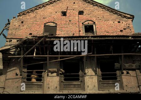 Ein Kind, das aus einem Fenster eines Hauses schaut, das durch die Erdbeben von 2015 in Bhaktapur, Nepal, teilweise beschädigt wurde. Stockfoto