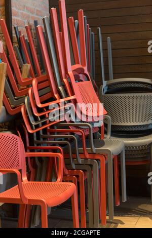 Nahaufnahme mehrerer roter und grauer Plastikstühle Einer übereinander in einer Ecke Stockfoto