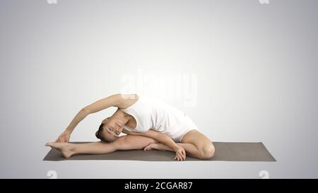 Schöne junge Frau trägt weiße Kleidung tun Yoga-Übung sitzen in einbeinigen King Pigeon (Single Pigeon) Pose auf Gradienten Hintergrund. Stockfoto