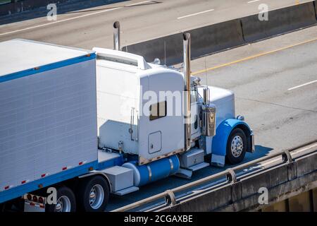 Leistungsstarke weiße klassische große Rig Diesel-Semi-Truck Transport gefroren Kommerzielle Ladung auf Kühlschrank Sattelauflieger läuft auf der gespaltenen Mehrzeilige Hi Stockfoto