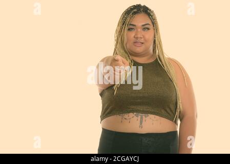 Studio Schuss von jungen glücklich Fett asiatische Frau lächelnd während Zeigt auf die Kamera Stockfoto