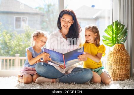 Glücklich liebende Familie. Hübsche junge Mutter Lesung ein Buch zu ihren Töchtern Stockfoto