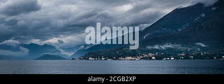 Landschaft des dunklen Comer Sees mit sehr bewölktem Himmel und Bergen, die in Norditalien liegt. Stockfoto