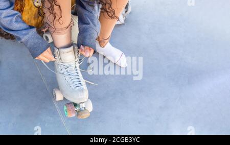 Draufsicht eines Mädchens, das ihre Schnürsenkel auf sie bindet Schlittschuhe auf einer Eisbahn Stockfoto