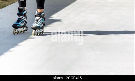 Beine eines Teenagers mit Inline-Skates auf einem Graue Spur Stockfoto