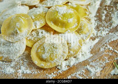 Leckere Ravioli mit Mehl, Kirschtomaten, Sonnenblumenöl und Basilikum auf dunklem Grund. Der Prozess der Herstellung von italienischen Ravioli. Nahaufnahme Stockfoto