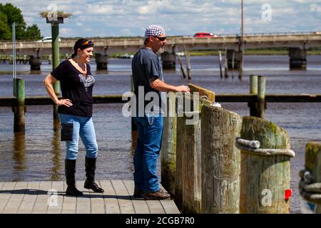 Chestertown, MD, USA, 08/30/2020: Ein Rocker mittleren Alters steht auf dem Dock am Chester River. Beide tragen Bandanna, Sonnenbrille, Jeans und le Stockfoto