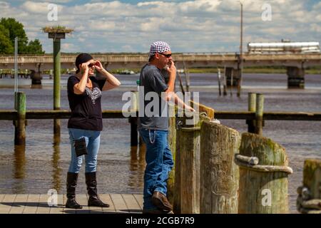 Chestertown, MD, USA, 08/30/2020: Ein Rocker mittleren Alters steht auf dem Dock am Chester River. Beide tragen Bandanna, Sonnenbrille, Jeans und le Stockfoto