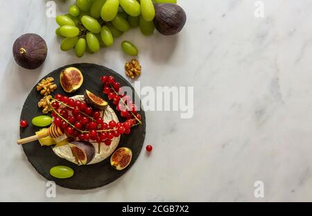 Im Ofen gebackener Camembert-Käse mit Honig, Früchten, Nüssen und Beeren Stockfoto