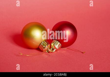 Rote und goldene Weihnachtskugeln liegen auf rotem Hintergrund, Nahaufnahme Stockfoto