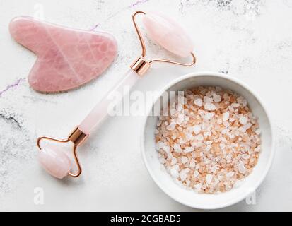 Set von natürlichen Bio-SPA-Kosmetik mit Orchideenblumen. Flach Lay Badesalz, Gesichtswalze, Orchideenblumen auf Marmorboden. Hautpflege, Beauty-Treat Stockfoto