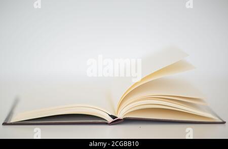 Nahaufnahme eines Hardcover-Notizbuchs mit sich drehenden leeren Seiten isoliert auf einem weißen Tisch. Stockfoto