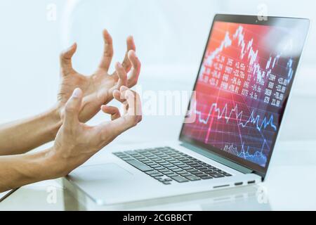 Börsencrash. Die gestresste Handbewegung des Investors, als er Geld auf seinem Online-Investmentkonto verlor, während er einen Laptop-Computer benutzte. Stockfoto