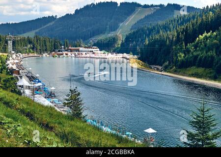 Bergsee umgeben von Bergen. Blau klares Wasser des Flusses. Felsensteine und grüner Wald Alpine Landschaft Stockfoto