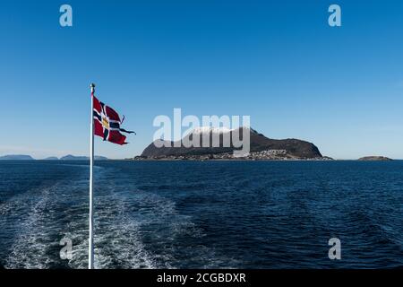 Norwegische Post oder Post Flagge gehisst auf Post von Postboat Winken im Wind mit offenem Meer und Bergen Sonniger Wintertag Stockfoto