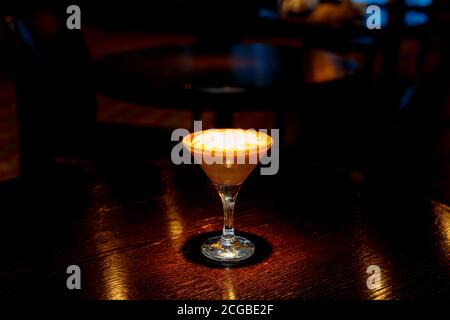 Kaffeecocktail mit weißem Schaum auf der Theke einer dunklen Bar. Stockfoto