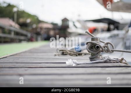 Nahaufnahme eines Seils, das um den Pier gebunden ist, festgezurrtes Schiff Stockfoto