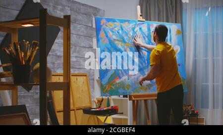 Kunstwerk mit Fingern mit bunten Ölfarbe auf großer Leinwand im Studio. Stockfoto