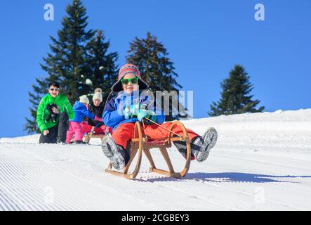 Familienspaß auf Schlittenfahrt im Schnee Stockfoto