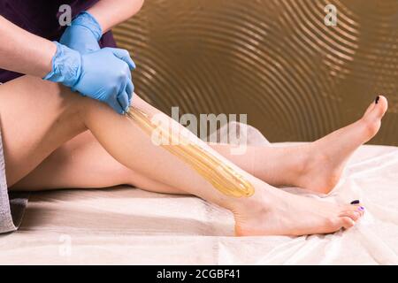 Frau mit Haarentfernung Verfahren auf Bein mit Zuckerpaste im Salon, close-up. Konzept der Kosmetologie. Stockfoto