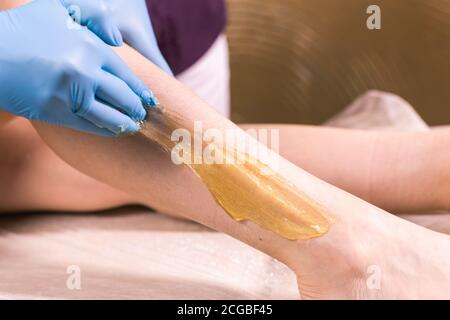 Frau mit Haarentfernung Verfahren auf Bein mit Zuckerpaste im Salon, close-up. Konzept der Kosmetologie. Stockfoto