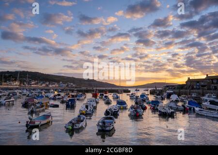 Lyme Regis, Dorset, Großbritannien. September 2020. Wetter in Großbritannien: Boote, die im Hafen von Cobb festgemacht sind, leuchten an einem kühlen Morgen im Küstenresort Lyme Regis unter einem wunderschönen herbstlichen Sonnenaufgang auf, wenn der Hochdruck in die Region übergeht und trockene und besiedelte Bedingungen vor einer vorhergesagten Mini-Hitzewelle bringt. Kredit: Celia McMahon/Alamy Live Nachrichten Stockfoto