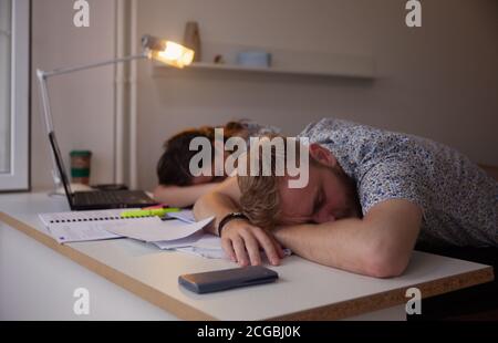 Zwei Studenten oder Mitarbeiter, die auf dem Tisch schlafen, vom Studium ausgestrahlt. Stockfoto