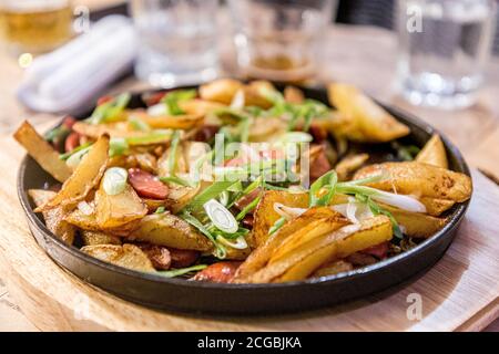 Bratkartoffeln mit Wurst auf einer schwarzen gusseisernen Pfanne in einem Restaurant. Stockfoto